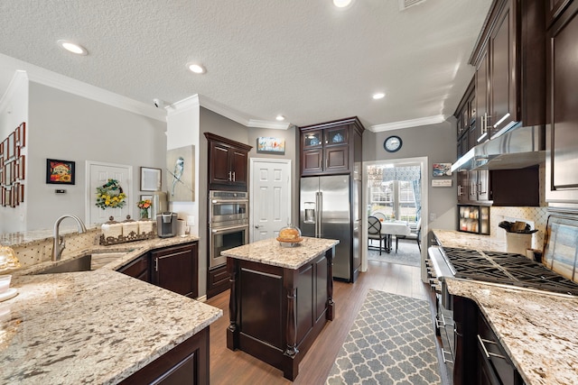 kitchen with a kitchen island, high quality appliances, light stone countertops, under cabinet range hood, and a sink