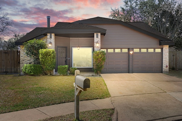 view of front of home featuring an attached garage, brick siding, fence, driveway, and a front yard