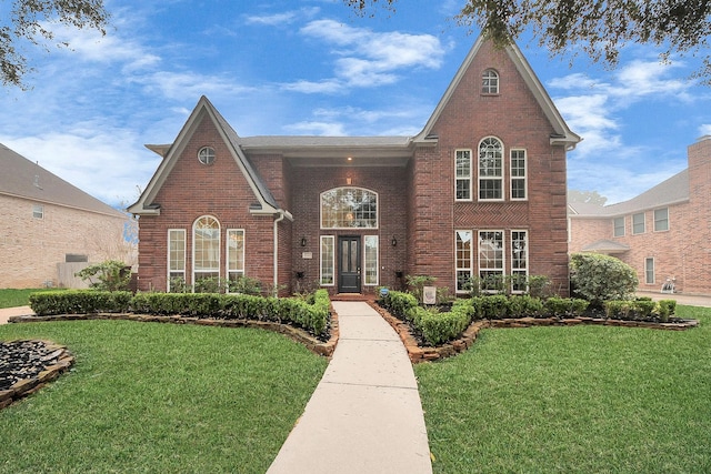 view of front facade featuring brick siding and a front yard