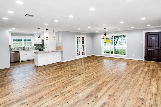 kitchen featuring light stone counters, white cabinetry, open floor plan, appliances with stainless steel finishes, and decorative light fixtures