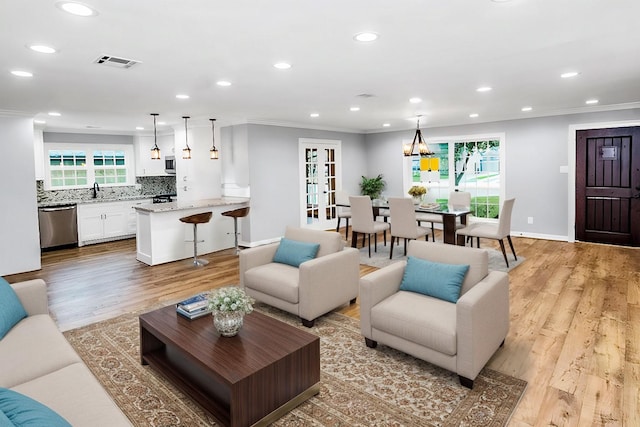 living room featuring visible vents, baseboards, ornamental molding, light wood-style floors, and recessed lighting