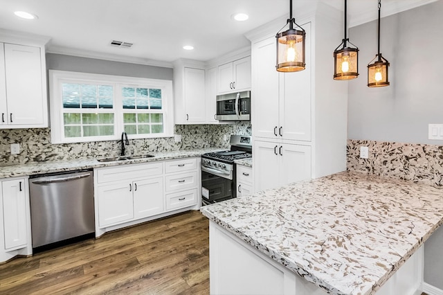 kitchen featuring stainless steel appliances, hanging light fixtures, white cabinets, a sink, and a peninsula