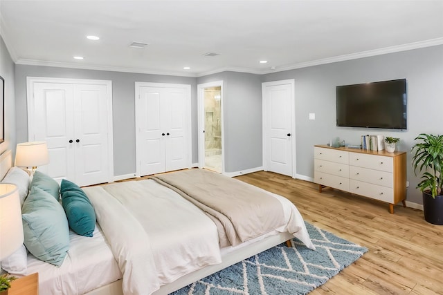 bedroom featuring baseboards, ornamental molding, light wood-style floors, two closets, and recessed lighting