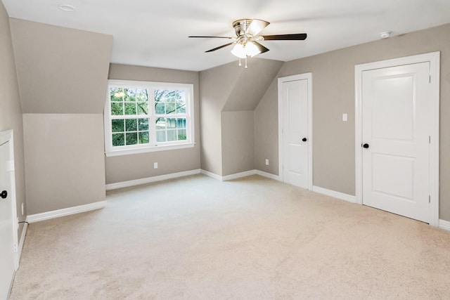 additional living space with light carpet, ceiling fan, vaulted ceiling, and baseboards