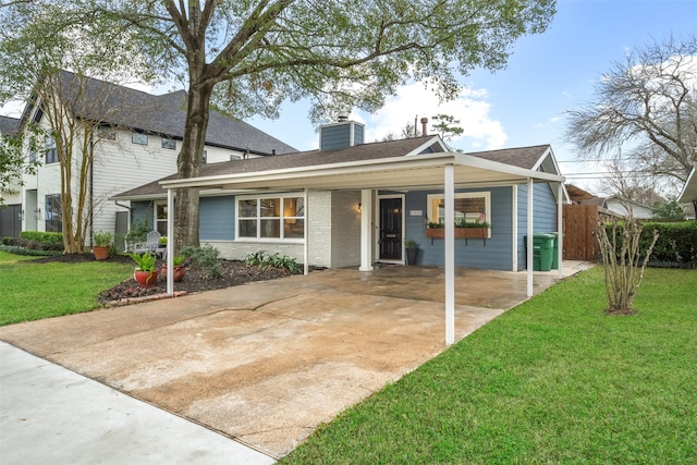 view of front facade featuring brick siding, concrete driveway, a carport, a front lawn, and a chimney