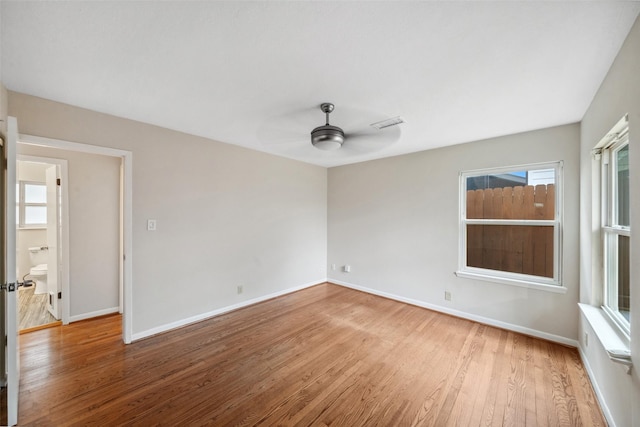 unfurnished room with ceiling fan, wood finished floors, visible vents, and baseboards