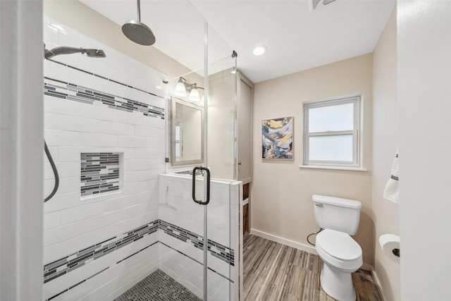 bathroom with toilet, a stall shower, baseboards, and wood finished floors