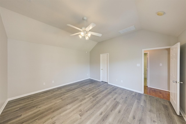 interior space with a ceiling fan, lofted ceiling, baseboards, and light wood finished floors