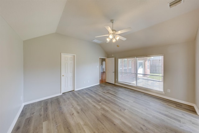 interior space featuring light wood-style floors, baseboards, visible vents, and vaulted ceiling