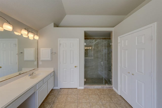 bathroom featuring a stall shower, baseboards, lofted ceiling, tile patterned flooring, and vanity