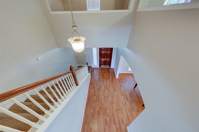 staircase featuring a towering ceiling, visible vents, and wood finished floors