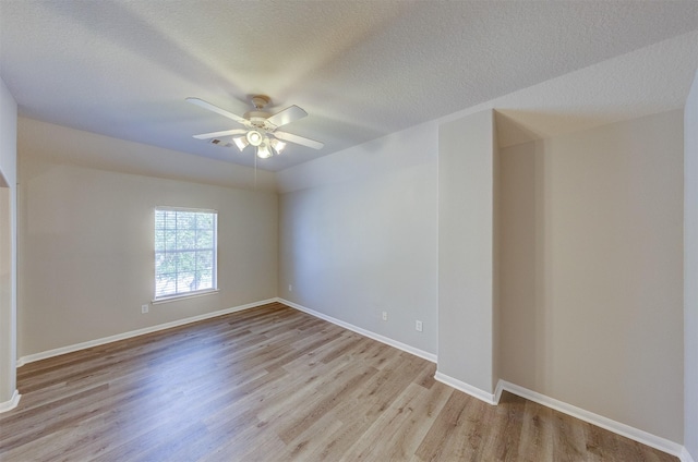 spare room featuring light wood-style floors, a textured ceiling, baseboards, and a ceiling fan