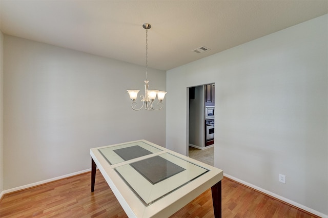 dining room with visible vents, a notable chandelier, baseboards, and wood finished floors