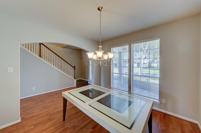 dining area featuring stairway, baseboards, arched walkways, and wood finished floors