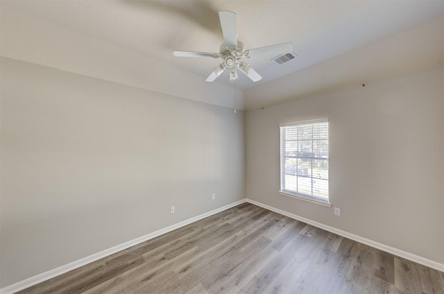 unfurnished room with visible vents, light wood-style flooring, a ceiling fan, vaulted ceiling, and baseboards