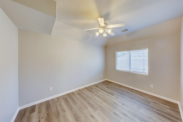 unfurnished room featuring lofted ceiling, baseboards, visible vents, and light wood-style floors