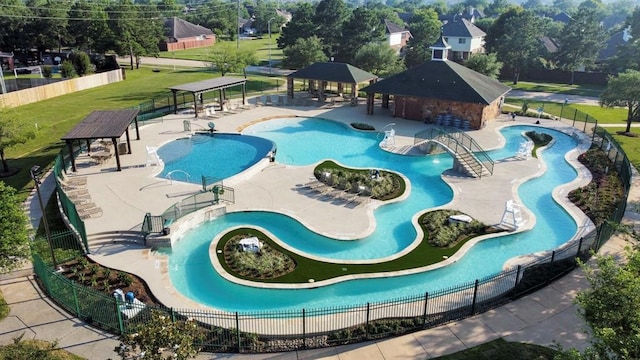 community pool featuring a gazebo, a water play area, a water slide, and fence