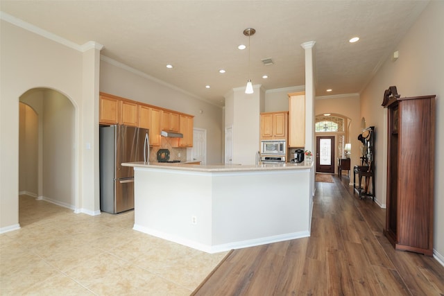 kitchen featuring light countertops, arched walkways, under cabinet range hood, and stainless steel appliances