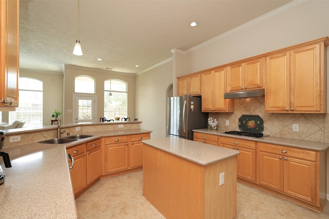 kitchen featuring under cabinet range hood, a sink, gas cooktop, freestanding refrigerator, and crown molding