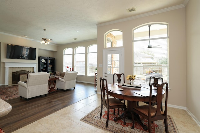 dining room featuring light tile patterned floors, a fireplace, baseboards, and ornamental molding