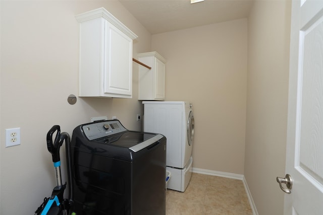 laundry room with light tile patterned floors, baseboards, cabinet space, and washer and clothes dryer