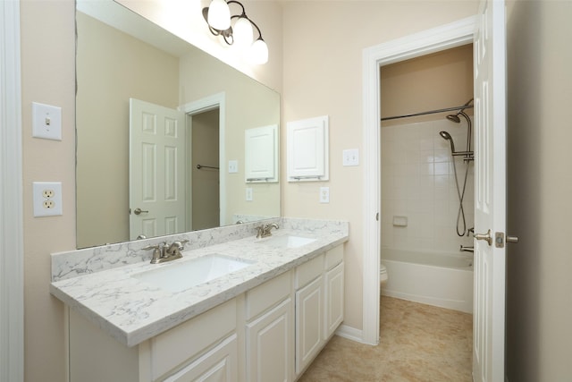 bathroom with double vanity, toilet, baseboards, and a sink