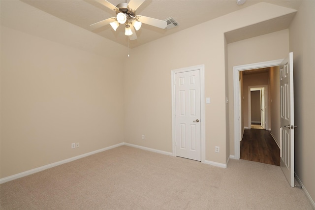 unfurnished room with visible vents, light carpet, baseboards, and ceiling fan