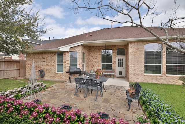 back of house featuring brick siding, a lawn, a patio, and fence