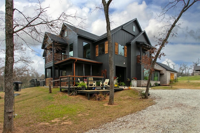 view of front of property with driveway, a balcony, a sunroom, a front lawn, and board and batten siding