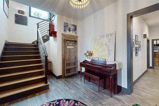 foyer entrance with stairs, a notable chandelier, wood finished floors, and baseboards