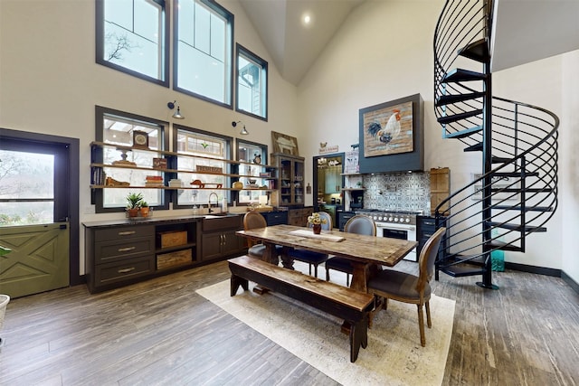 dining area featuring stairs, high vaulted ceiling, wood finished floors, and baseboards