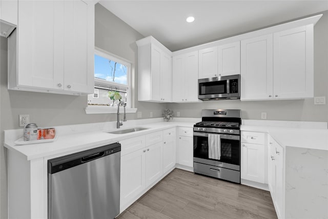 kitchen featuring a sink, white cabinets, stainless steel appliances, and light countertops