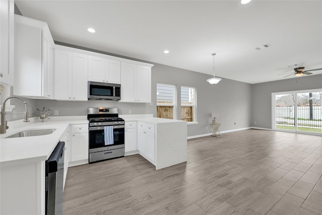 kitchen featuring open floor plan, stainless steel appliances, light countertops, white cabinetry, and a sink