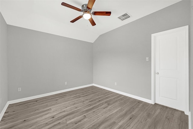 spare room with baseboards, visible vents, a ceiling fan, wood finished floors, and vaulted ceiling