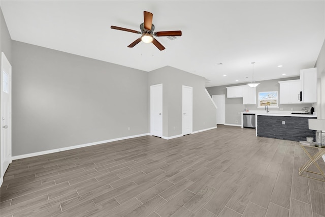 unfurnished living room featuring a ceiling fan, recessed lighting, light wood-style flooring, and baseboards