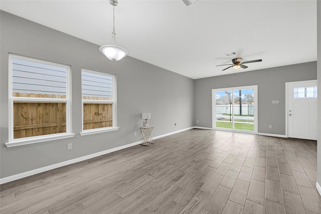 unfurnished living room with light wood-style floors, visible vents, ceiling fan, and baseboards