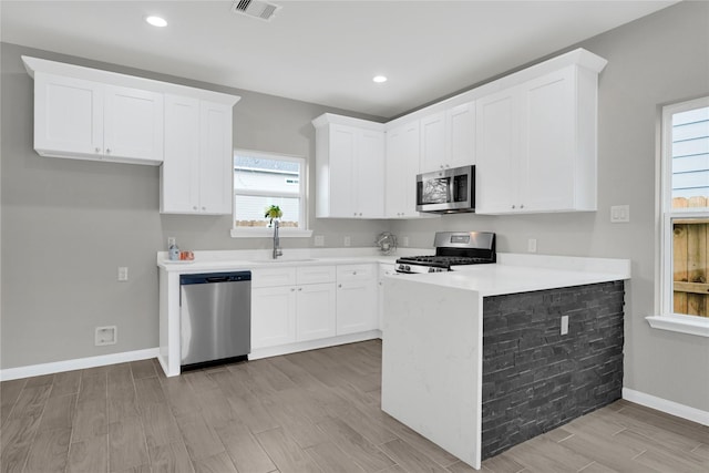 kitchen with stainless steel appliances, a sink, visible vents, white cabinetry, and light countertops