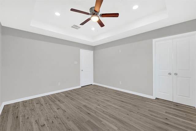 interior space featuring a tray ceiling, wood finished floors, and visible vents