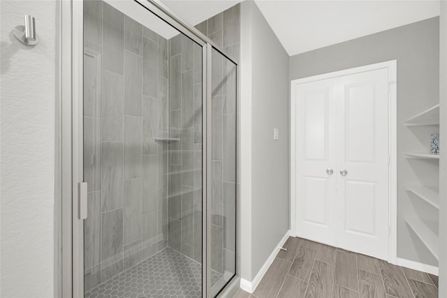 bathroom featuring a stall shower, baseboards, and wood finish floors