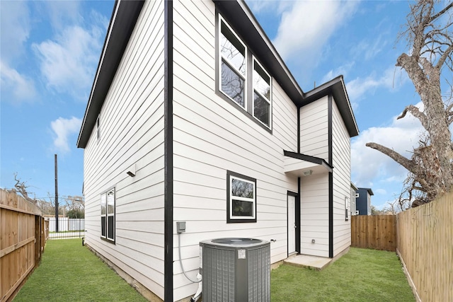 back of house with central AC, a lawn, and a fenced backyard