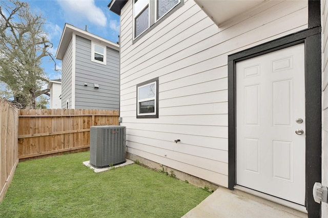 exterior space with fence, a lawn, and central air condition unit