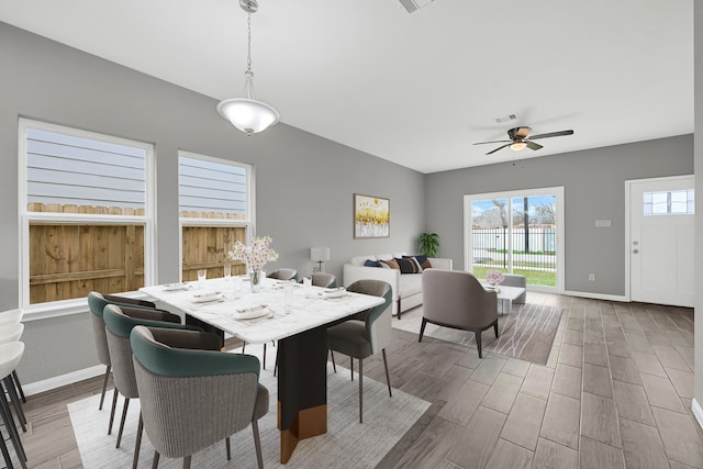 dining area with light wood finished floors, a ceiling fan, visible vents, and baseboards