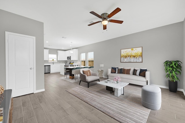 living room with wood tiled floor, baseboards, a ceiling fan, and recessed lighting