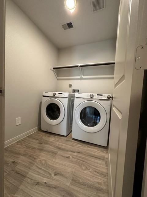 laundry area with laundry area, washing machine and clothes dryer, visible vents, and baseboards