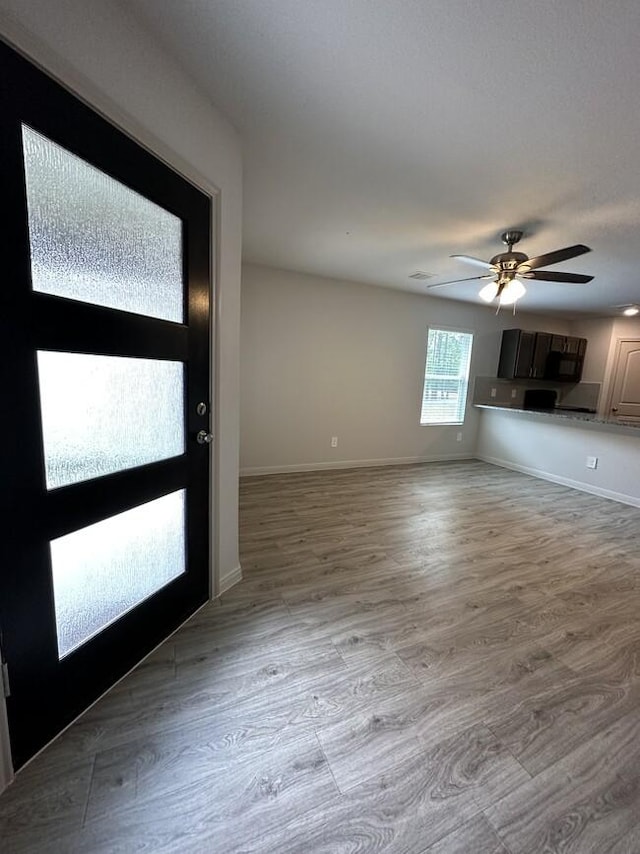 entryway featuring ceiling fan, light wood-style flooring, and baseboards