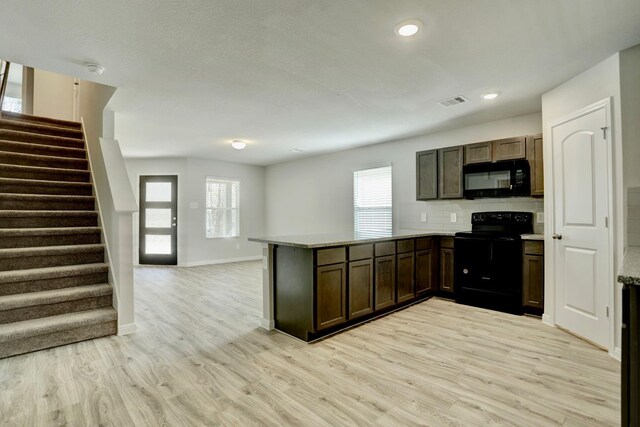 kitchen with light wood-style flooring, backsplash, open floor plan, a peninsula, and black appliances