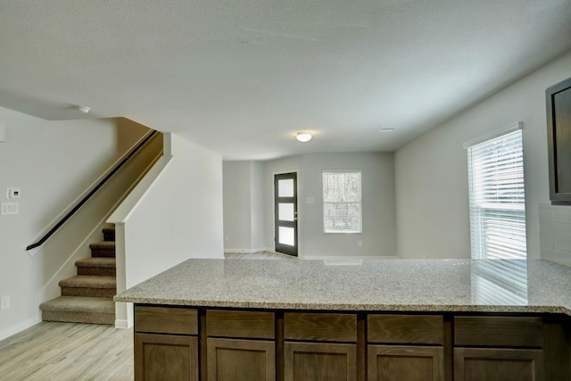 kitchen featuring a healthy amount of sunlight, light stone countertops, open floor plan, and light wood-style floors