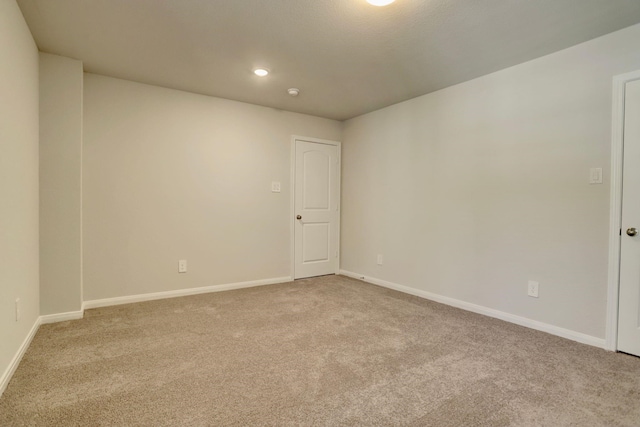 spare room featuring baseboards, recessed lighting, and light colored carpet