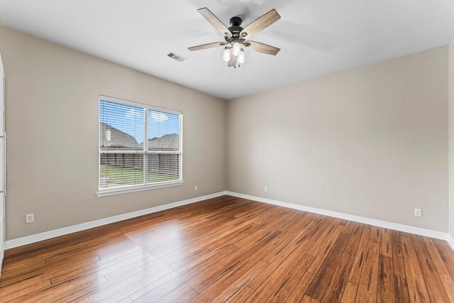 empty room with baseboards, ceiling fan, visible vents, and wood finished floors