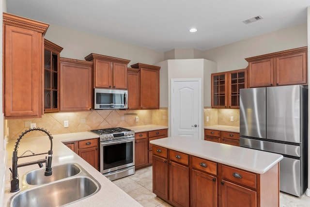 kitchen featuring light countertops, stainless steel appliances, a center island, a sink, and visible vents